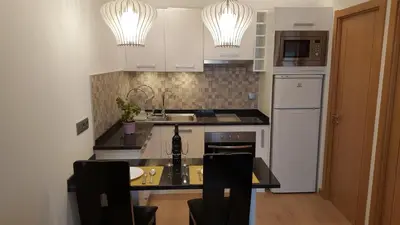a kitchen with white cabinets and a black counter top at Apartamento Cardoso II. A 5 minuto a pé da praia do Peneco in Albufeira