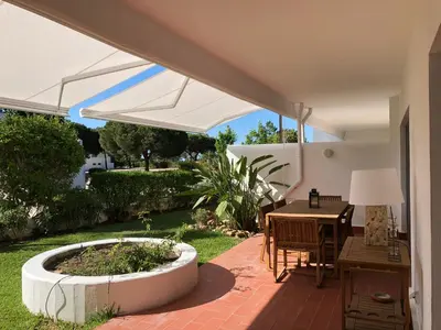 a patio with a table and a white umbrella at Victory Village 1B Quinta do Lago in Quinta do Lago
