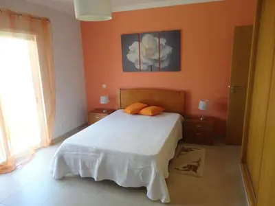 a bedroom with a bed with orange walls and a window at Villa 48 in Quarteira