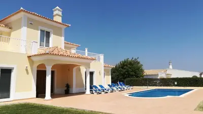 a villa with a swimming pool and blue chairs at Villa 48 in Quarteira