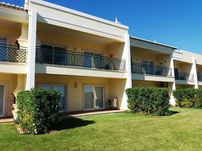 a large apartment building with bushes in the yard at Apartment Coelha Beach - Pool - Free Wi-Fi - Air Con in Albufeira