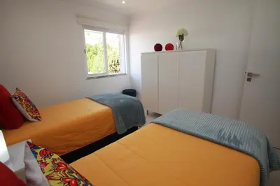 a small bedroom with two beds and a window at Apartamento A Palmeira in Albufeira