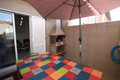 a table with a colorful blanket and an umbrella at Apartamento A Palmeira in Albufeira