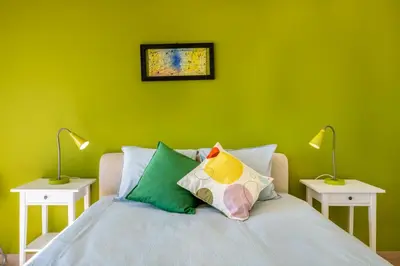 a green bedroom with a bed with pillows and two lamps at Vita Portucale ! Quarteira Sea View in Quarteira