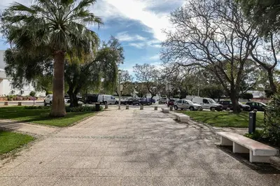 a row of benches in a park with parked cars at T0 Vilamoura Downtown in Vilamoura