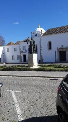 a white building with a statue in front of it at Residencial Condado in Faro