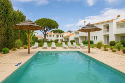 a swimming pool with two umbrellas and a house at Vale do Lobo - Casa de La Rosa in Vale do Lobo
