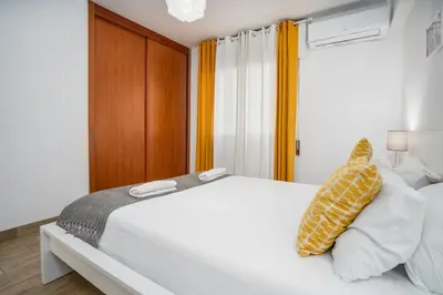 a bedroom with a white bed with yellow and white pillows at #002 Donalds Flat by Home Holidays in Albufeira