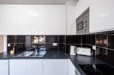 a white kitchen with a sink and a microwave at #002 Donalds Flat by Home Holidays in Albufeira