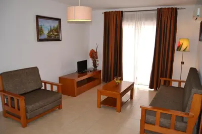 a living room with a couch and chairs and a television at Apartamentos Cabrita in Albufeira