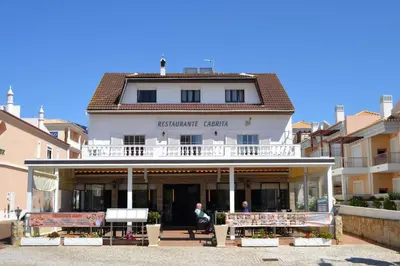 a man sitting on a bench in front of a building at Apartamentos Cabrita in Albufeira