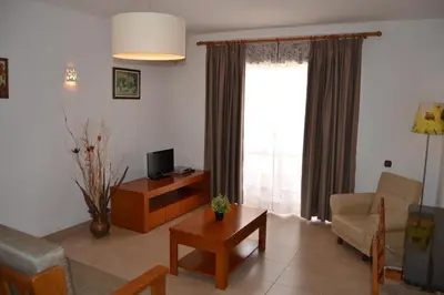 a living room with a couch and a tv and a table at Apartamentos Cabrita in Albufeira