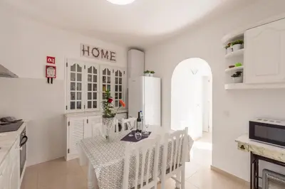 a white kitchen with a table and chairs and a refrigerator at Fisherman's Beach Home 2BR 2BA AC Wi-Fi in Albufeira