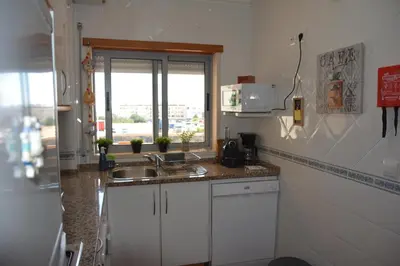 a kitchen with white cabinets and a sink and a window at Balcony View Albufeira in Albufeira