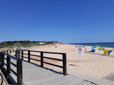 a wooden boardwalk on a beach with a no swimming sign at COLINA FÉRIAS- Garagem & WIFI in Quarteira
