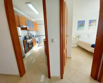 a room with a kitchen and a bedroom with a bed at COLINA FÉRIAS- Garagem & WIFI in Quarteira