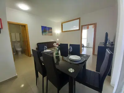 a dining room table with black chairs and a dining room at Dunas 3- Elegante, 150mt Praia, Wifi in Quarteira