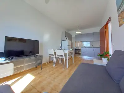 a living room with a kitchen and a table with chairs at Mira Atlântico 13- Terraço Com Vista Mar e Cidade, Wifi, 80mt Praia in Quarteira