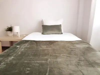 a bed in a small room with a table at cosy2bedroomapartment in Loulé