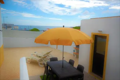 a table with a yellow umbrella on a balcony at Vila Baltum - Free private parking - Wifi - Airco # by bedzy # in Albufeira