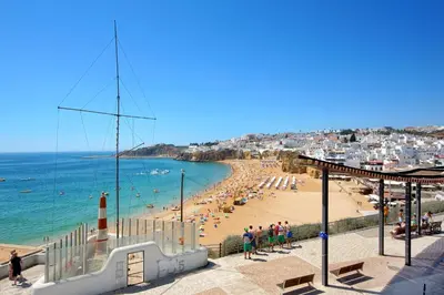 a view of a beach with people and a lighthouse at Casa Indigo- Perfect location & Sea View by DreamvillasAlbufeira in Albufeira