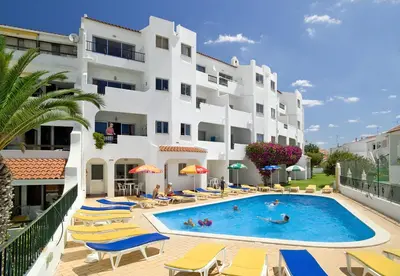 a hotel with a swimming pool and chairs and a building at Silmar in Albufeira
