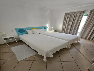 a bedroom with a large white bed with a blue headboard at Hotel Adelaide in Faro