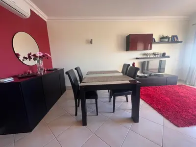 a dining room with a table and a red wall at Apartamento Vista Golfe Mar Vilamoura in Vilamoura