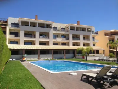 a large building with a swimming pool in front of it at Apartamento Vista Golfe Mar Vilamoura in Vilamoura