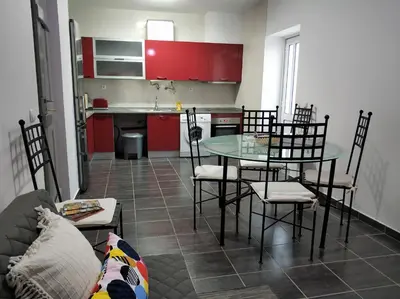 a kitchen with red cabinets and a table and chairs at Sleep & Go Faro Airport Guest House in Faro