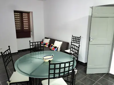 a glass table and chairs in a room with a couch at Sleep & Go Faro Airport Guest House in Faro