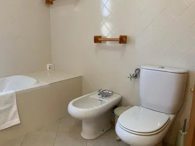 a white bathroom with a toilet and a sink at Guest House Alfarrobeiras in Albufeira