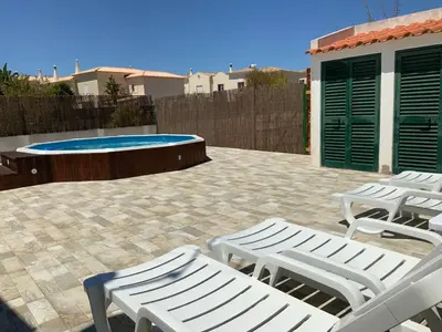 two white lounge chairs and a swimming pool at Guest House Alfarrobeiras in Albufeira