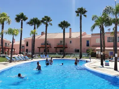 a group of people in a swimming pool with palm trees at Albufeira Villa Santa Maria in Albufeira