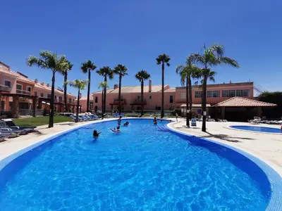 a group of people in a swimming pool with palm trees at Albufeira Villa Santa Maria in Albufeira