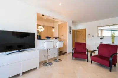 a living room with two chairs and a flat screen tv at Marina Vilamoura Aquamar 104 By Vilamoura Sun in Vilamoura