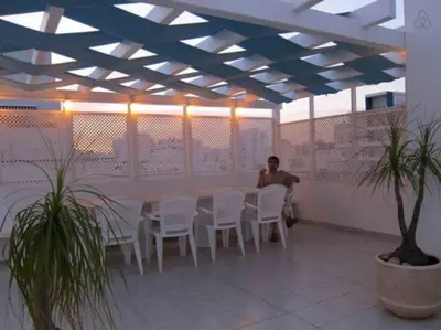 a man sitting at a table with white chairs at Oceanides Beachfront Apartments in Quarteira