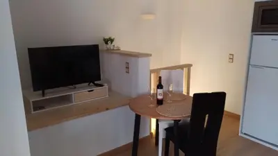 a kitchen with a table with a television and a table with a bottle of wine at Apt Cardoso 3 ao lado da Praia Peneco in Albufeira