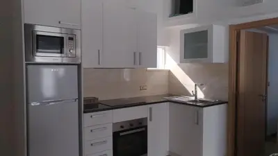 a kitchen with white cabinets and a sink and a refrigerator at Apt Cardoso 3 ao lado da Praia Peneco in Albufeira