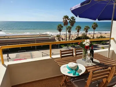 a balcony with a table and a train on the beach at T1 Praiamar 3 Vista Fabulosa in Quarteira
