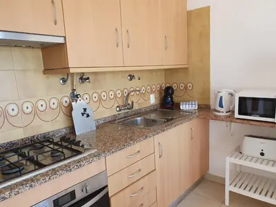 a kitchen with wooden cabinets and a sink and a microwave at T1 Praiamar 3 Vista Fabulosa in Quarteira