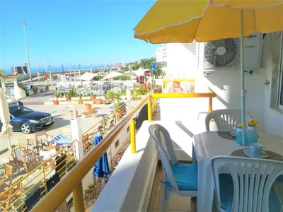 a balcony with a table and a yellow umbrella at T1 PraiaMar RC com Ar-Condicionado in Quarteira