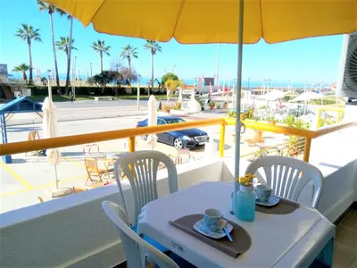 a table and chairs with an umbrella on a balcony at T1 PraiaMar RC com Ar-Condicionado in Quarteira