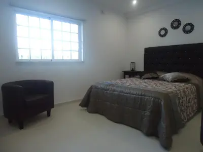 a bedroom with a bed and a chair and a window at VIVENDA L'OLIVIER in Quarteira