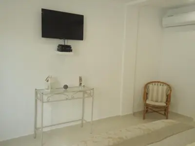 a room with a chair and a television on a wall at VIVENDA L'OLIVIER in Quarteira