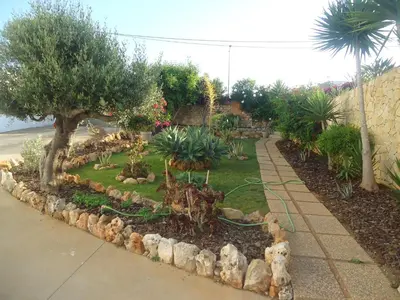 a garden with trees and plants and a sidewalk at VIVENDA L'OLIVIER in Quarteira