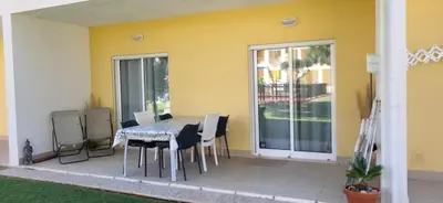 a patio with a table and chairs and a yellow wall at Apartamento T2 Encosta sao jose in Albufeira