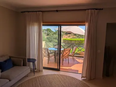 a living room with a couch and a balcony with a table at Corcovada 37 in Albufeira