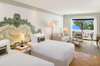 a hotel room with two beds and a living room at Pine Cliffs Hotel, a Luxury Collection Resort, Algarve in Albufeira