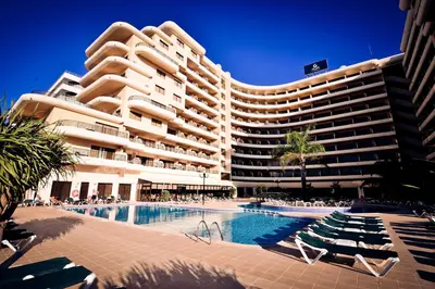 a large hotel with a swimming pool in front of a building at Vila Gale Marina in Vilamoura